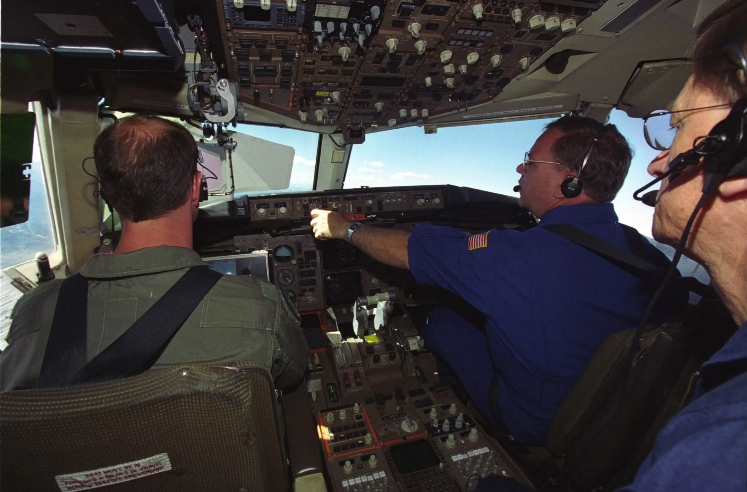 Three men in the cockpit of an airplane.