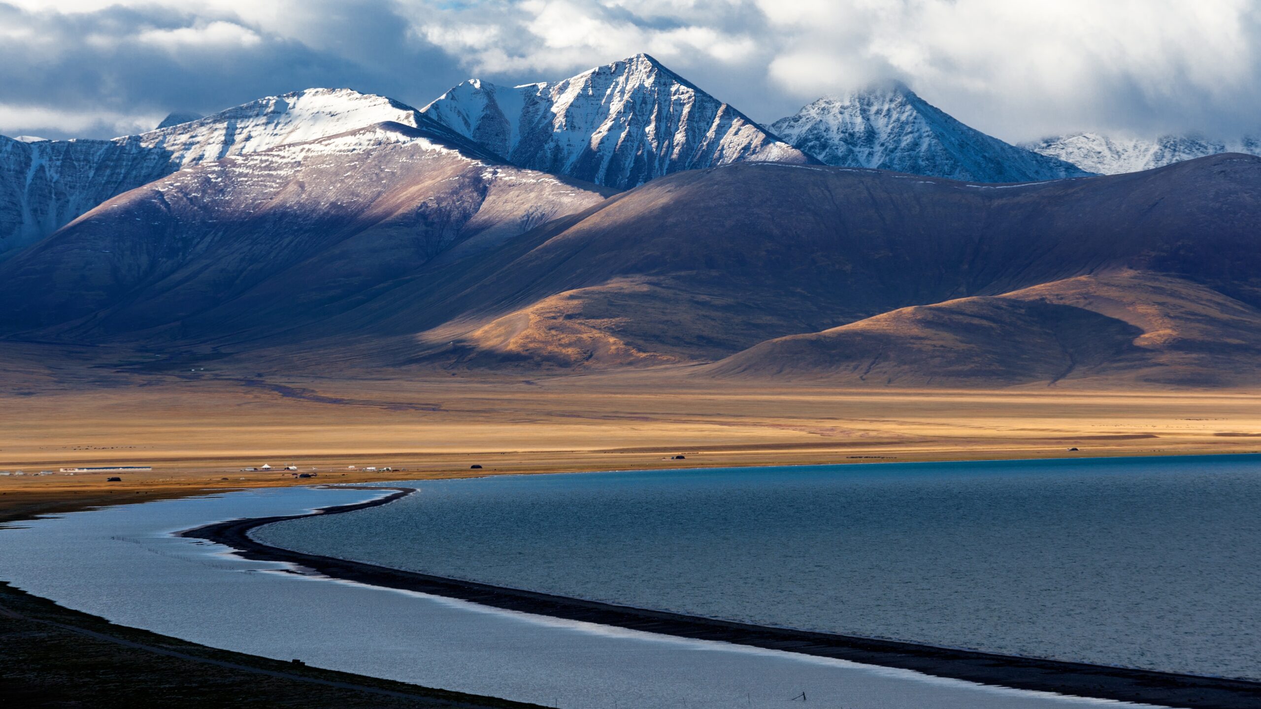 A lake in the foreground with snow-capped mountains in the background