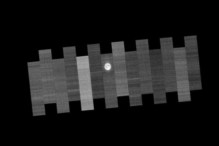 Parallel grayscale scan strips from Landsat 9, with the Moon appearing near the centerline of alternating strips before eventually appearing in all strips.
