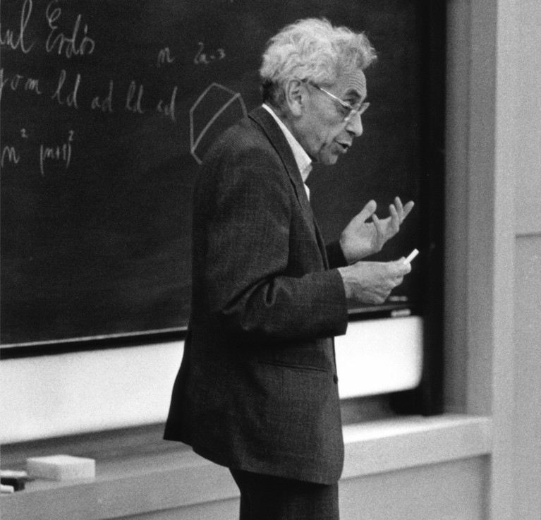 Black and white photograph of Paul Erdõs, gesturing in front of a blackboard.