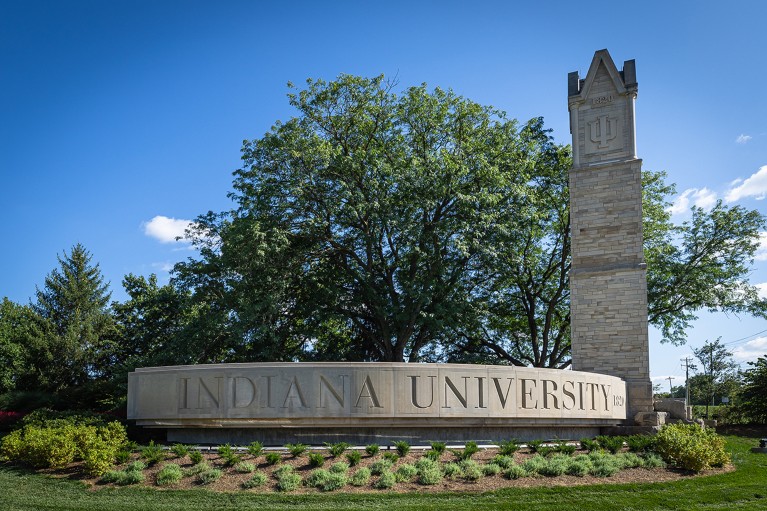 The Indiana University campus entrance in Bloomington with a sign of the university’s name in a stone statue.