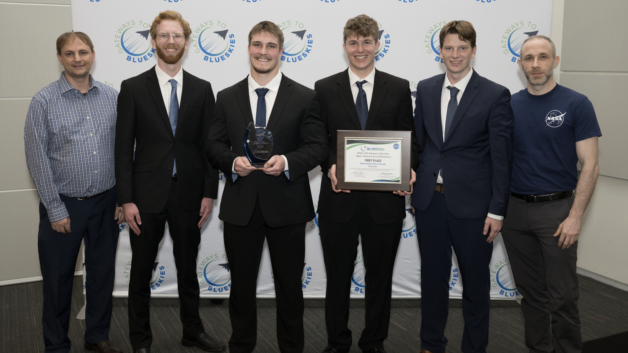 The members of team WINGMAN stand in the center of the photo holding their first place certificate for NASA's Gateways to Blue Skies Competition.