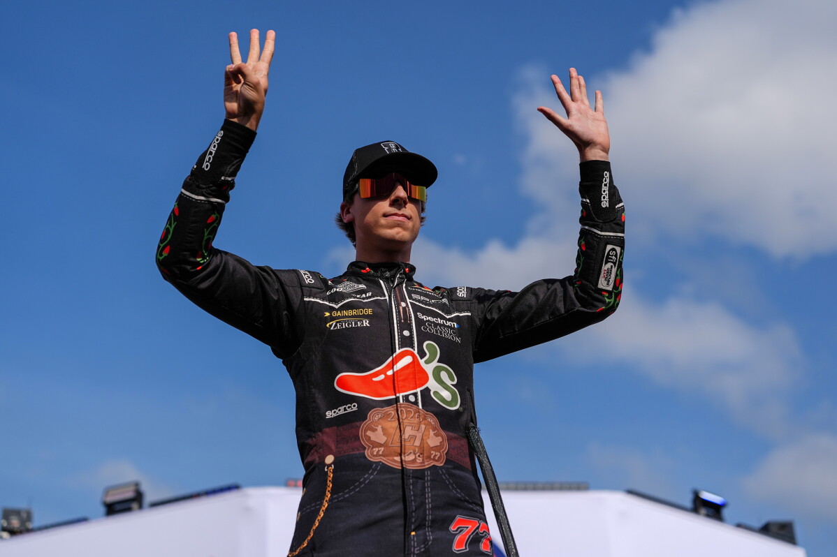 Carson Hocevar holds up eight fingers in honor of late driver Kyle Busch prior to a NASCAR Cup Series auto race, Sunday, May 24, 2026, in Charlotte, N.C. (AP Photo/Matt Kelley)