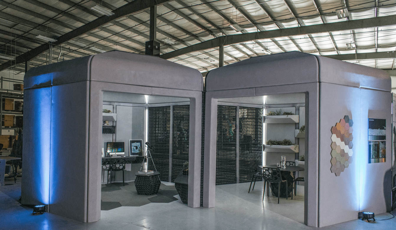 Two boxy structures, one with an office-like interior and the other with an eating area, side-by-side in a hangar-like location