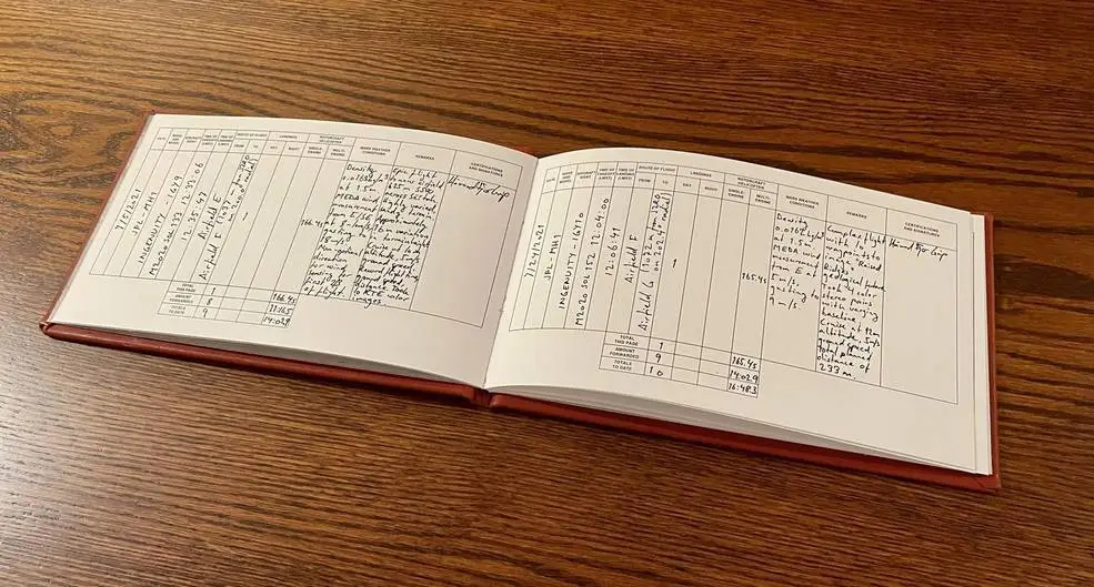 An opened flight log on a wooden desk.