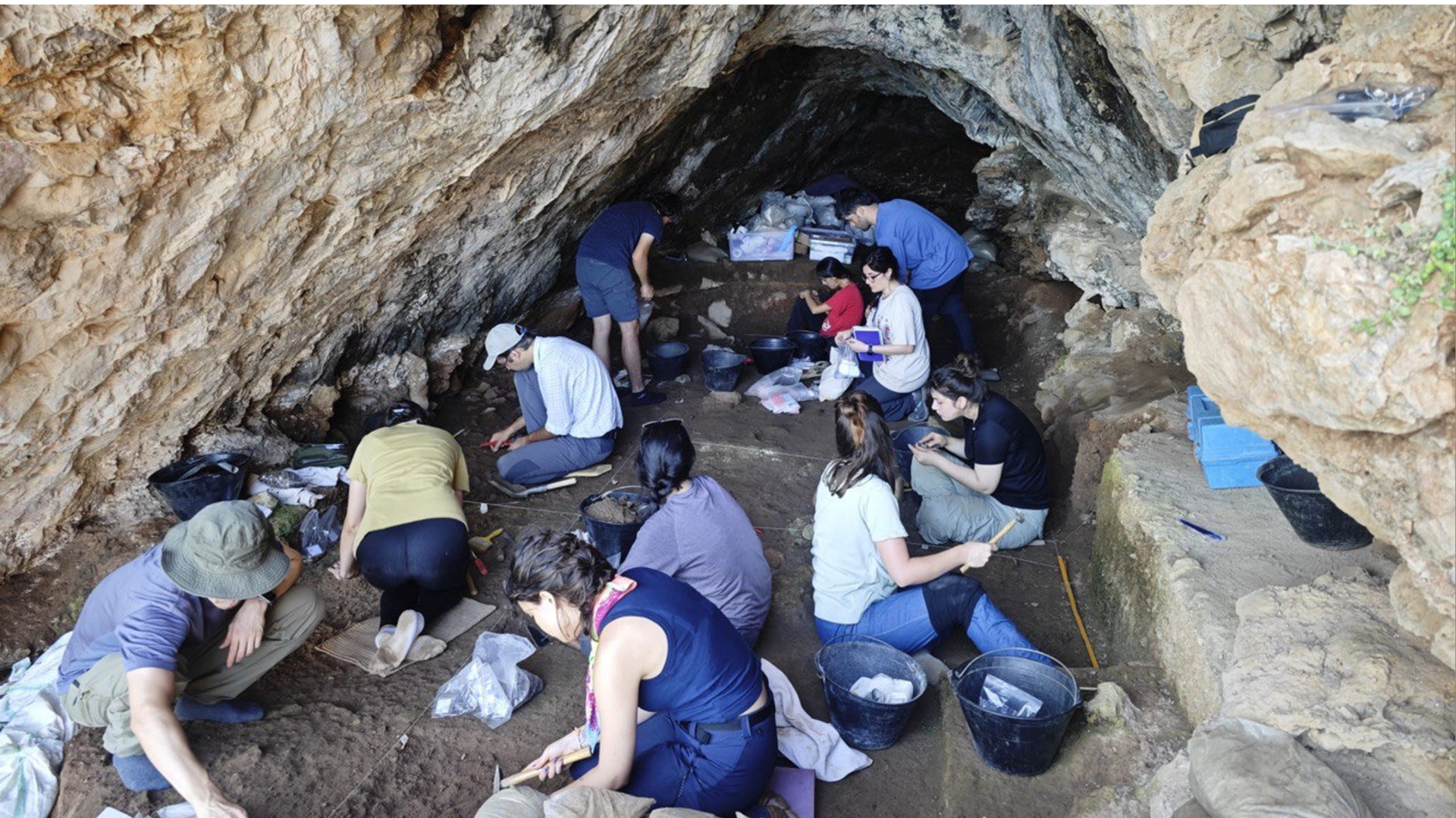 A group of archaeologists in a cave with tools.