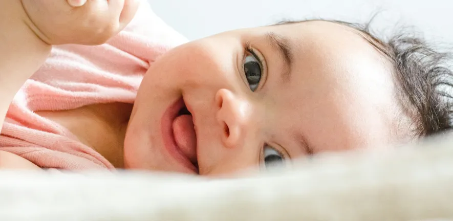 Baby smiling while lying on a bed